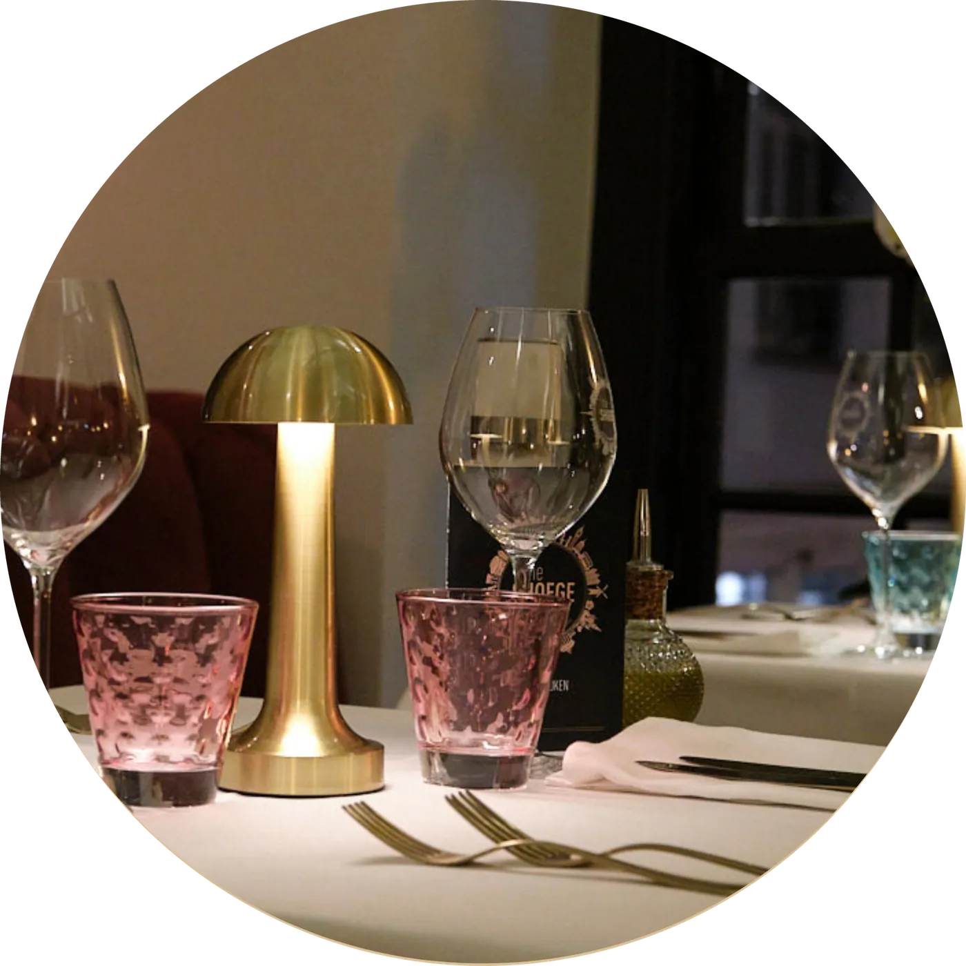 Glazen en een gouden tafellamp op een gedekte tafel