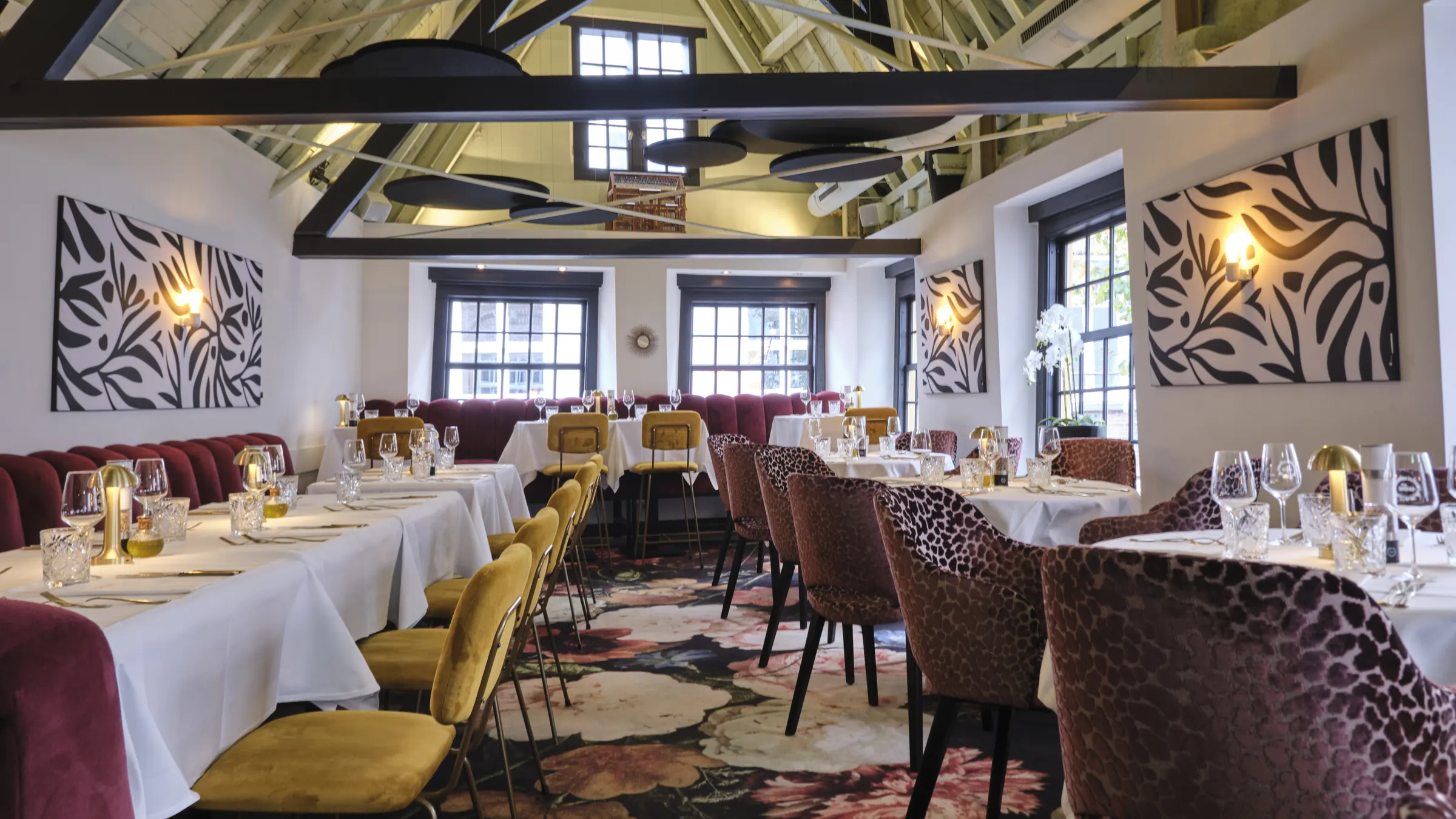 The LOFT op de eerste verdieping, met houten dakspanten, gedekte tafels en fluwelen stoelen